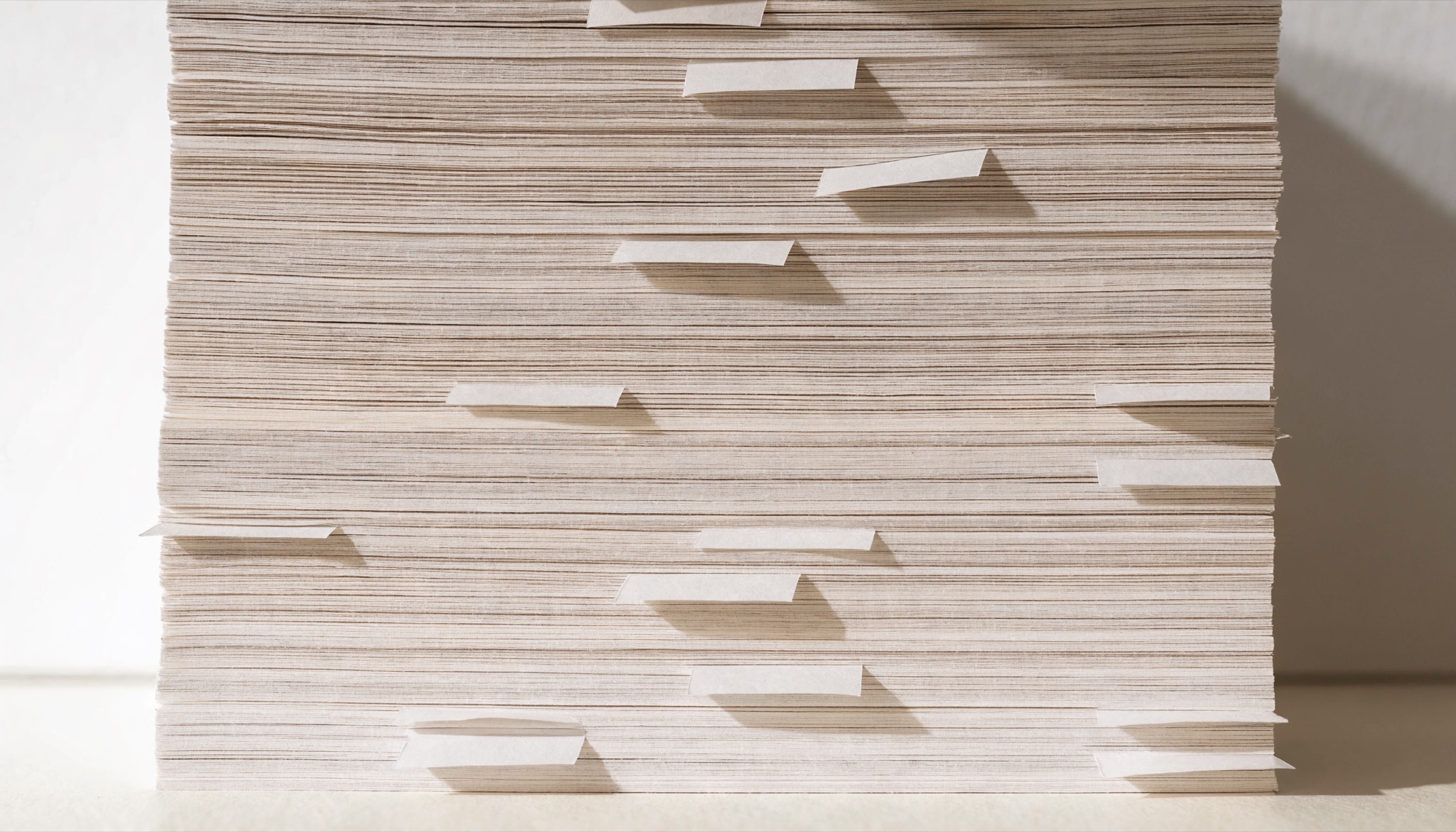 The compressed edge of a tall stack of printed paper, with plain tabs protruding at intervals.